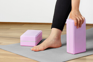 Woman yoga workout with yoga blocks on yoga mat indoor. Healthy lifestyle.