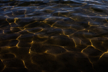 Texture of the water surface. Reflection of light in water, Dark background, Golden lines