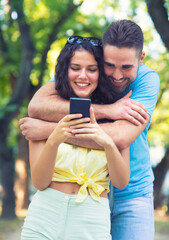 Young smiling couple taking selfie with phone in the summer nature