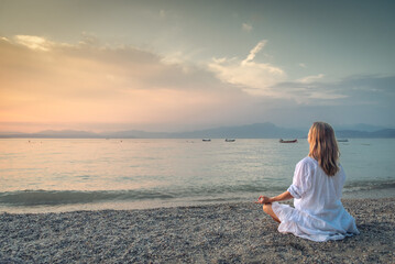 Fototapeta na wymiar Woman meditating at the Garda Lake. Sunset.