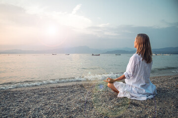Woman meditating at the Garda Lake. Sunset.