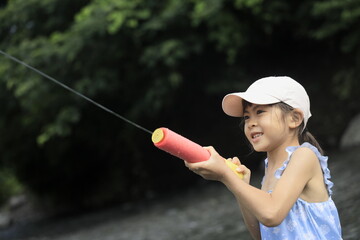 水鉄砲で川遊びをする女子小学生 (7歳)