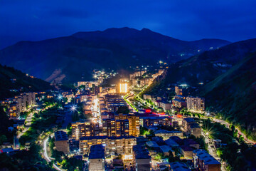 Night city from a bird's eye view. The light of houses and cars. A beautiful city with rivers, bridges and beautiful buildings. City among the mountains, Kapan, Armenia