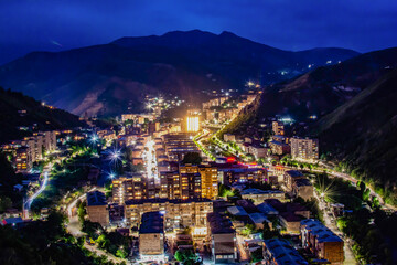 Night city from a bird's eye view. The light of houses and cars. A beautiful city with rivers, bridges and beautiful buildings. City among the mountains, Kapan, Armenia