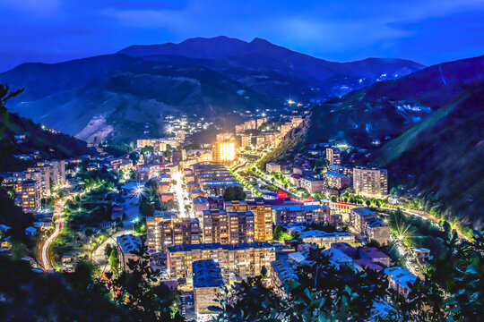 Night city from a bird's eye view. The light of houses and cars. A beautiful city with rivers, bridges and beautiful buildings. City among the mountains, Kapan, Armenia