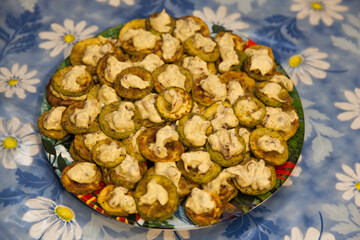 Pieces of fried zucchini in garlic mayonnaise laid out on the table.