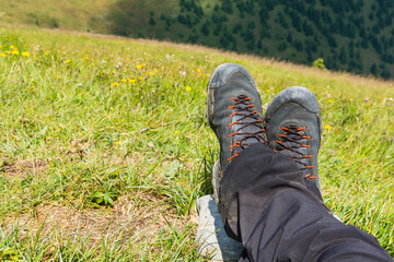 Wet approach shoes and pants drying on the legs of a tourist resting on the green grass. - 519143113