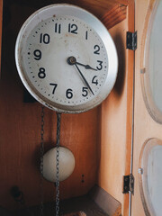 Retro old wooden antique clocks with the pendulum hanging on the wall. Clock face. Interior design,...