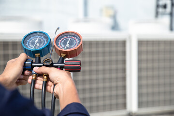 Technician is checking air conditioner ,measuring equipment for filling air conditioners , service and maintenance air conditioner .