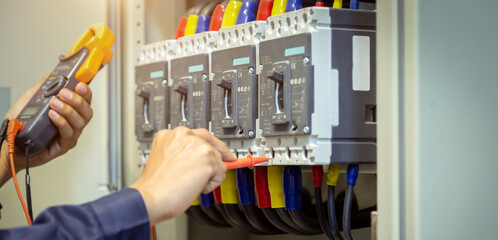 Electrical engineer using measuring equipment to checking electric current voltage at circuit breaker and cable wiring system , Electrical service concept .