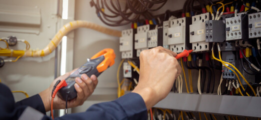 Electrical engineer using measuring equipment to checking electric current voltage at circuit...