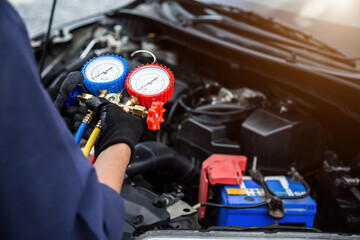 Fototapeta premium Close up hand of auto mechanic are to use measuring manifold gauge for filling car air conditioners. Concepts of fix and checking for repair service , Car service concept .