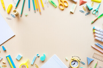 Frame of various school supplies on a light peach background, flat lay. Place for text.