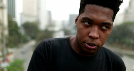 Frustrated young black African man standing outside in city