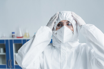 Scientist in hazmat suit and protective mask in laboratory.