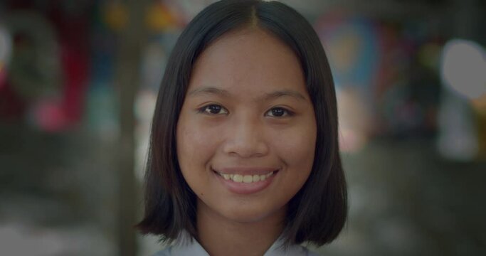 A happy smiling cute Asian high school student girl who has short hair and tan skin.