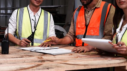 Four heavy industrial engineers stand together in a steel factory. Design discussions, meetings, seminars in industrial plants. Engineer teach and write on clipboard to use metal processing machines.