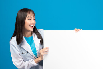 Smiling doctor holding blank banner or card with stethoscope on blue background