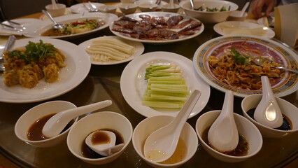 Asian-style shared meal with various dishes served on a round dining table, representing family dining, social gathering, and traditional food culture.