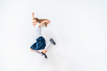 Fototapeta na wymiar happy schoolgirl in a school uniform, jumping on a white background in the studio. the little girl is ready for school conceptual school. the holidays begin. Advertising discounts