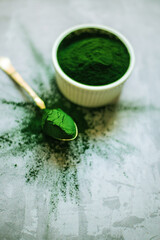spirulina powder in white plate on concrete background