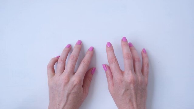 View from above. Women's hands type on the keyboard with all ten fingers. Nails with pink polish