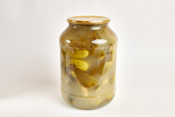 A glass jar with canned cucumbers on a white background.