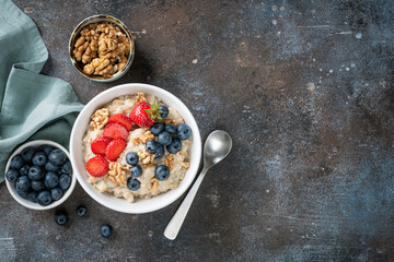 Healthy breakfast bowl of oatmeal with berry fruits and walnuts, top view copy space