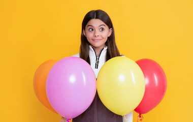 Fototapeta na wymiar happy amazed kid with party colorful balloons on yellow background