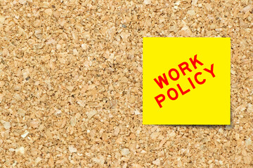 Yellow note paper with word work policy on cork board background with copy space