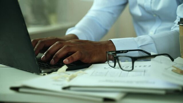 Close up of handsome mans hands working on laptop at office. African American male police officer hands filling reports at his laptop at a table at the police department. High quality 4k footage