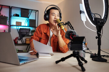 Young man follwign scenario when recording voiceover for his blog