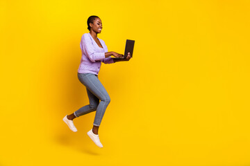 Full length profile photo of energetic person run jump use wireless netbook isolated on yellow color background