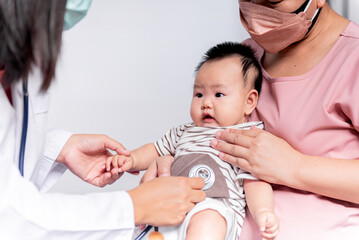 The doctor is using a stethoscope, checking the respiratory system Of a 3-month-old Asian baby...