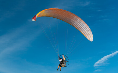 The people was playing a Paramotor which a small aircraft, flying on bule sky Beautiful nature background to recreation concept.