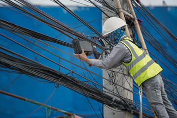 An electrical engineer checks and repair the fiber optics system on a power pole,. to engineer and...