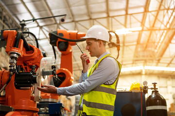 Male engineer checking and inspection control a robot arm machine welding steel in an industrial factory, Fast and highly secure.