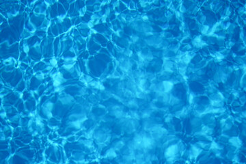 Blue water in swimming pool with sun reflection, motion of ripple wave, top view.