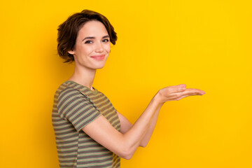 Naklejka premium Side profile photo of young beautiful lady holding hands promote new product recommend isolated on yellow color background