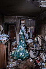 a specialist in a protective suit from a cleaning company cleans a destroyed housing after a fire