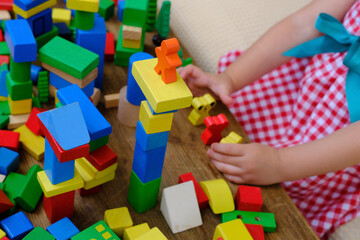 little four year old boy has fun playing at home with wooden blocks building tower under isolation,...
