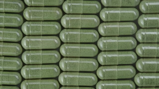 Green powder capsules Superfood, close up. Mooring, spirulina capsules