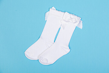 high white children's socks with big bows for festive clothes on a blue background top view