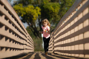 Child runners run in park. Boy running in the park in summer in nature. Outdoor sports and fitness, exercise and competition learning for kid development.