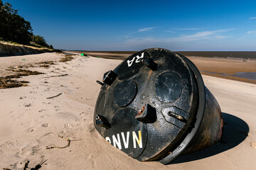 Black signaling beacon aground on the beach, Kiyu, San José, Uruguay. Another green signaling beacon can be seen in the background