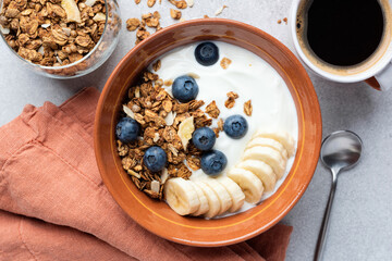 Yogurt bowl with chocolate granola, blueberries and banana. Top view. Healthy breakfast bowl