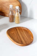 Empty wooden plate on kitchen table. Empty round wooden oak dish, board, tray. Empty and template mockup with place for food. Kitchen utensils