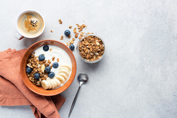 Breakfast granola cereal bowl with yogurt and fruits on grey concrete background. Top view copy...