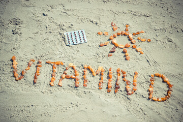 Medical pills, inscription vitamin D and shape of sun on sand at beach, summer time and healthy...