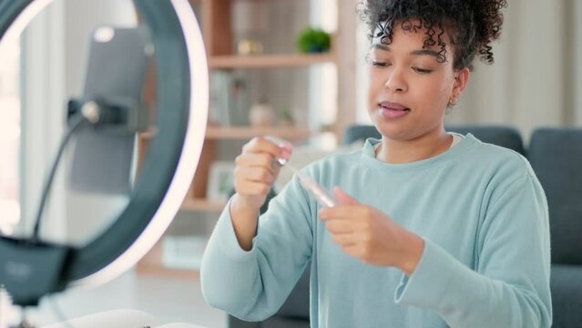 Female vlogger streaming while doing a makeup tutorial live on her phone at home. One happy and smiling woman applying lipgloss or lipstick to her lips while recording a video for her online viewers